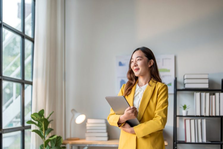 Young asian businesswoman is smiling while holding a laptop in her office